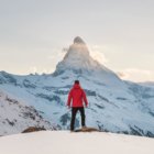 Mann mit roter Jacke im Winter mit Blick auf Zermatt