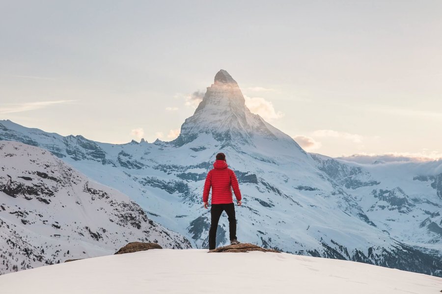 Mann mit roter Jacke im Winter mit Blick auf Zermatt